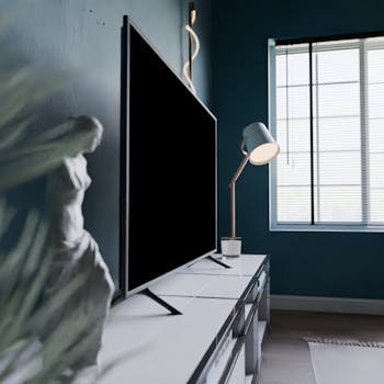 A stylish modern room featuring a statue, flat screen TV, and window light.