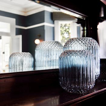 Stylish glass jars reflecting in a mirror, creating a refined indoor decor ambiance.